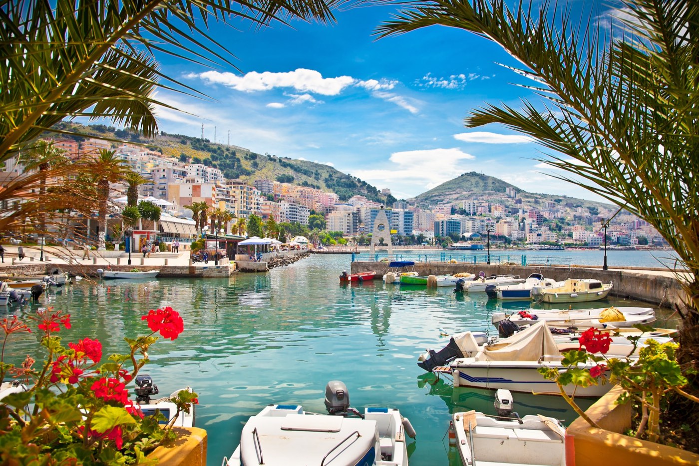 Saranda harbour framed by palm trees and fishing boats